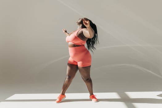 Full length of active African plus size woman in sportswear doing stretching exercises in fitness studio photo
