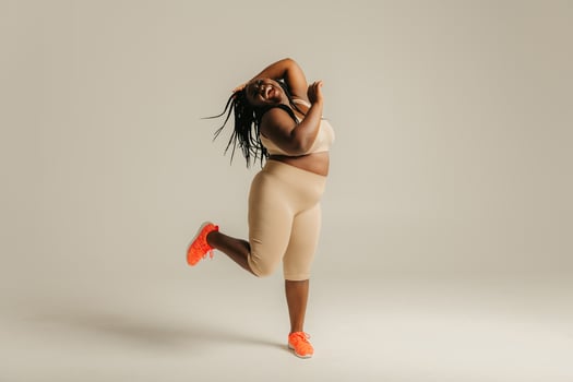 Full length happy plus size African woman in sportswear dancing on studio background photo