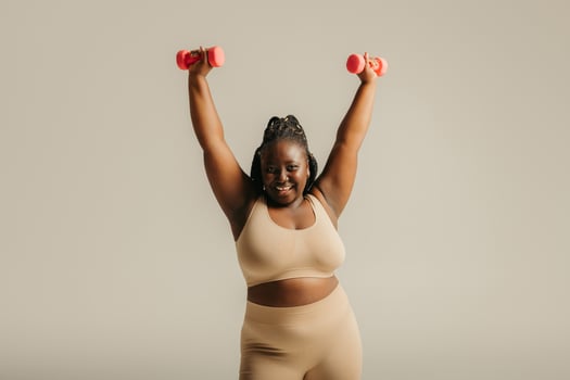 Beautiful curvy African woman in sportswear radiating confidence while exercising on studio background photo