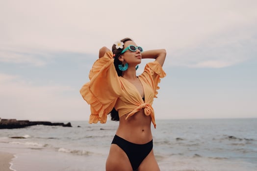 Fashionable young woman stretching out hands while enjoying day on the beach photo