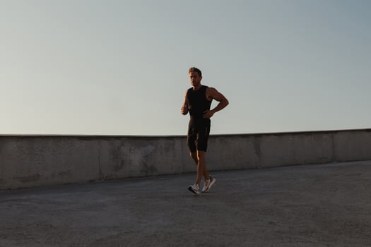 Athletic young man in sports clothing running by the road while enjoying morning jog outdoors photo