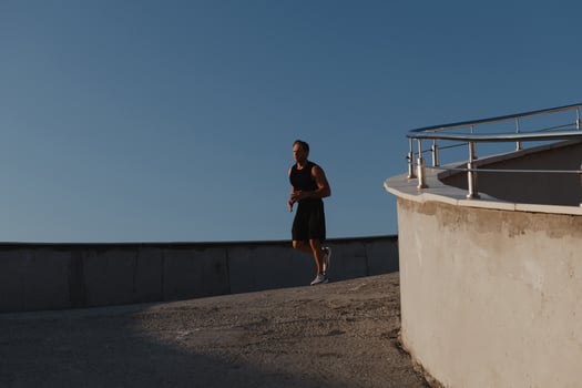 Confident young man in sports clothing running by the road while enjoying morning jog photo