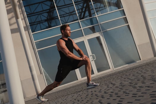 Confidant male athlete doing stretching exercises outdoors against urban building photo