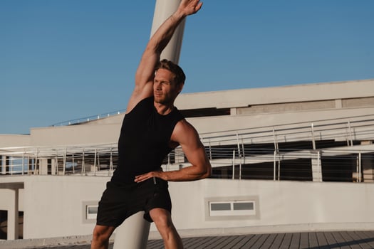 Confidant young muscular man in sports clothing doing morning exercises outdoors photo