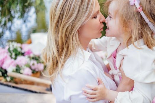 Young charming woman kisses her cute laughing little daughter. photo