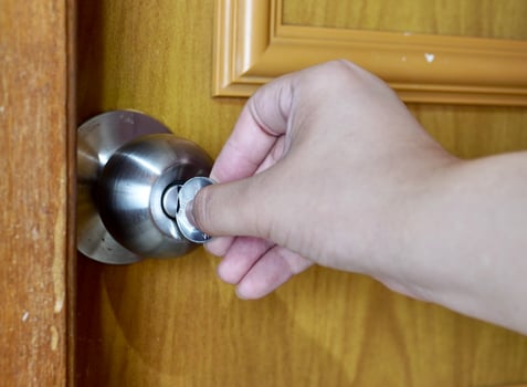 Hand holding emergency coin key to unlock round cylinder metal bathroom door knob isolated on horizontal background. photo