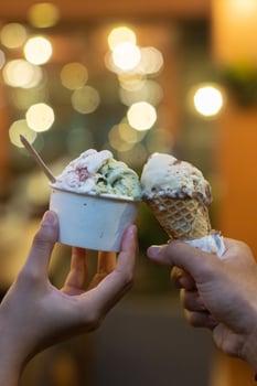 Close up hand of a person holding a cup and a cone of ice cream with blurred background photo