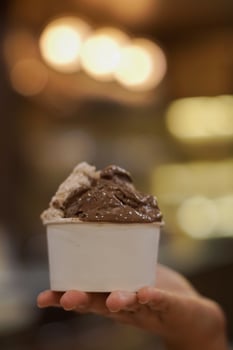 Close up hand of a person holding a cup of ice cream with blurred background photo