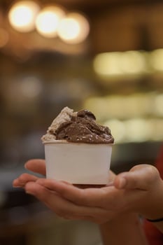 Close up hand of a person holding a cup of ice cream with blurred background photo