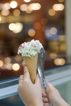 Close up hand of a person holding a cone of ice cream with blurred background photo