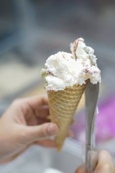 Close up hand of a person scooping ice cream in to a cone with blurred background photo