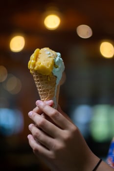 Close up hand of a person holding a cone of ice cream with blurred background photo