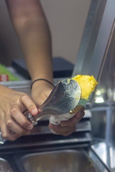 Close up hand of a person scooping ice cream in to a cone with blurred background photo