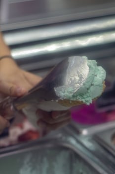 Close up hand of a person scooping ice cream in to a cone with blurred background photo