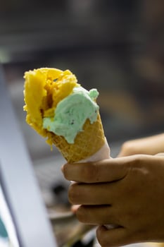 Close up hand of a person holding a cone of ice cream with blurred background photo