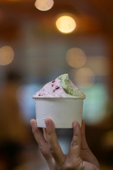 Close up hand of a person holding a cup of ice cream with blurred background photo