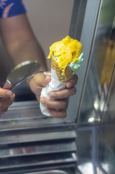 Close up hand of a person scooping ice cream in to a cone with blurred background photo