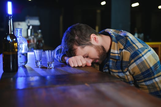 Drunk man sleeps at bar counter, alcohol addiction photo