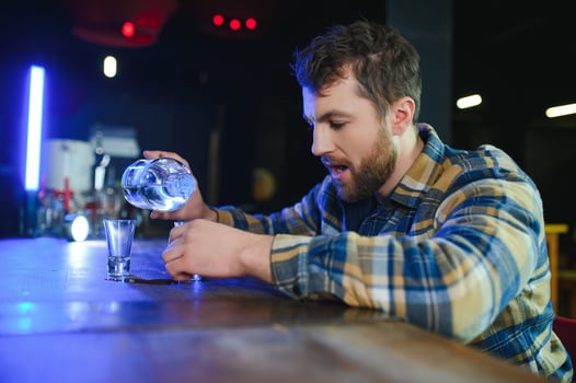 It was a hard day. Depressed young man drinking vodka in bar photo