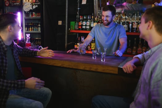 Attractive bartender is smiling and taking order of two men sitting at bar counter in pub photo