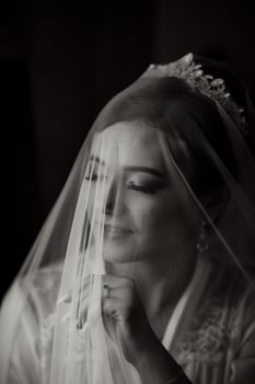 A woman is wearing a veil and looking at the camera. The veil is made of a mesh material and covers her face. The woman's expression is serious and contemplative photo