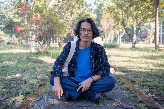 A man wearing a plaid shirt sits in the park relaxed and happy. photo