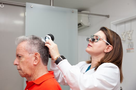 Dermatologist performing a trichoscopy to a senior male patient. photo