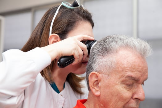 Dermatologist performing a trichoscopy to a senior male patient. photo