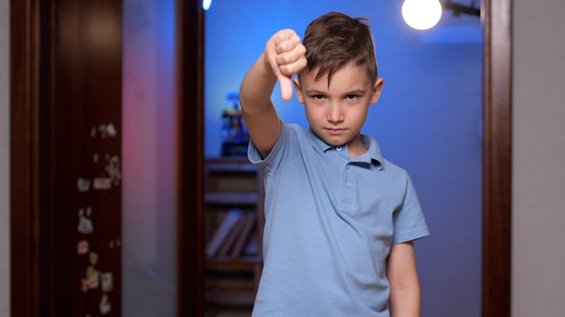 Upset child showing thumbs down gesture at home photo
