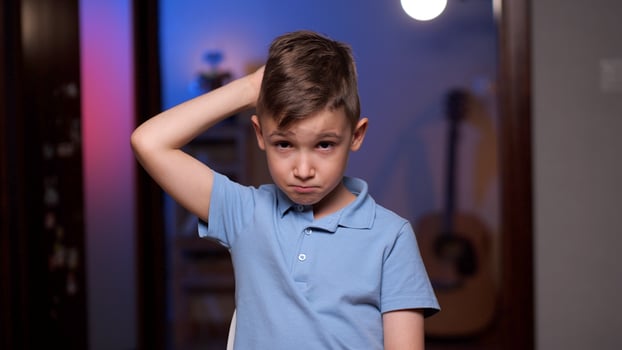 Young boy scratching head feeling confused photo