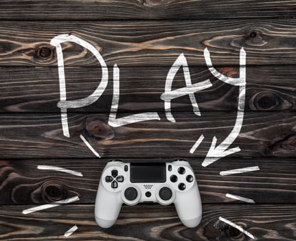 white gamepad on a dark wooden background. word play and an arrow pointing to the gamepad. photo