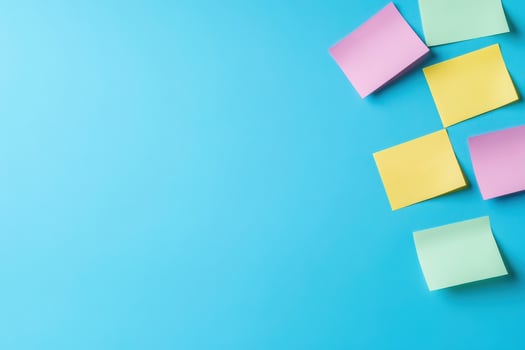 A collection of colorful sticky notes in pink, yellow, and green positioned creatively against a solid blue backdrop. photo