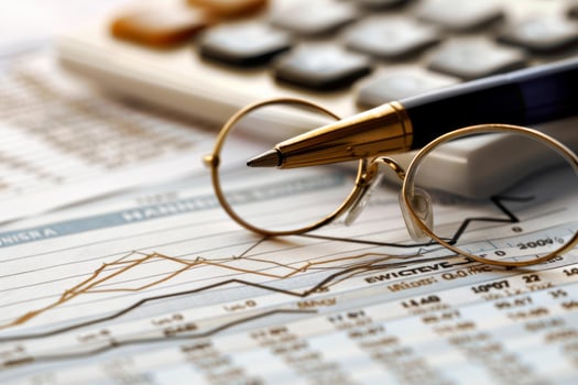 Businessman analyzing financial charts with calculator, pen and eyeglasses photo