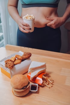 To eat or not. Cheerless plump woman looking at the burger while thinking to eat it or not photo