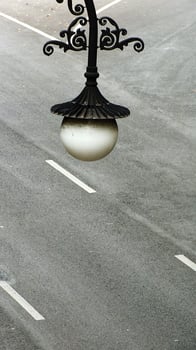 A street light with a white shade is hanging from a pole on the asphalt street road. The light is surrounded by a white line. Copy space for text photo