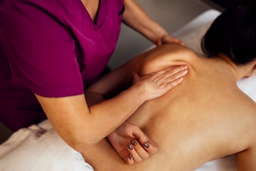 Happy young caucasian girl getting back massage in spa salon photo