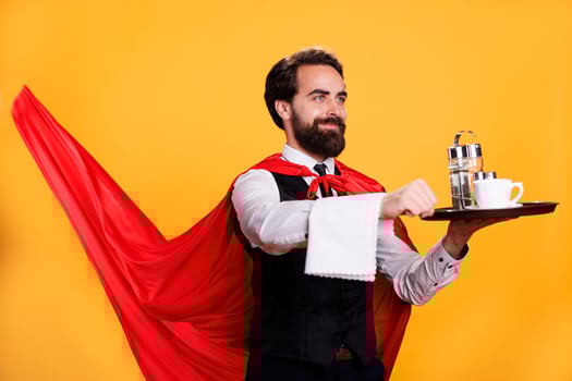 Luxury waiter with cape holds tray in studio, feeling confident and powerful while he is serving people at restaurant. Man with butler occupation indicated determination, dining personnel. photo