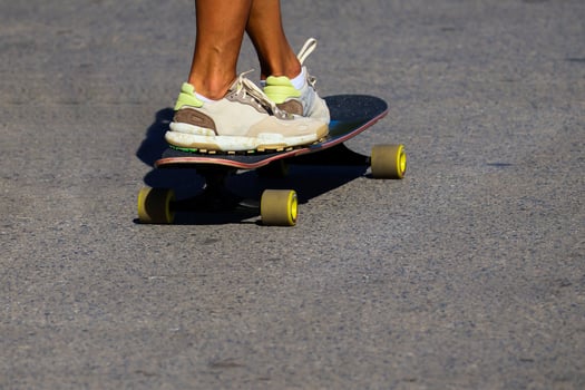 Girl in bright sneakers skateboarding. Woman's legs on a skateboard. photo