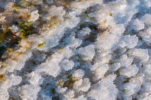 Weathered ice and frozen snow in the form of needle crystals on the bank of the Tiligul Estuary on a sunny day photo