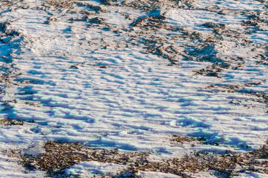 Weathered ice and frozen snow in the form of needle crystals on the bank of the Tiligul Estuary on a sunny day photo