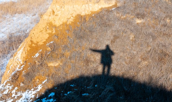 Black shadow, silhouette of a man with a raised hand on the shore of the estuary in winter photo