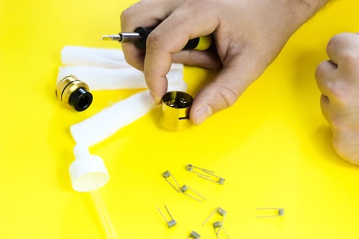 electronic cigarette details, Vata, coils, drip, spring, nippers on a yellow background. man's hands change springs in vape photo