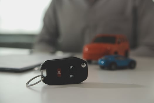 Young man receives a key from car salesman. After agreeing to a contract for rent or sale of a car at workshop, loan car, insurance, sale, buying car and finance concept. photo