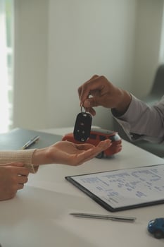 Young man receives a key from car salesman. After agreeing to a contract for rent or sale of a car at workshop, loan car, insurance, sale, buying car and finance concept. photo