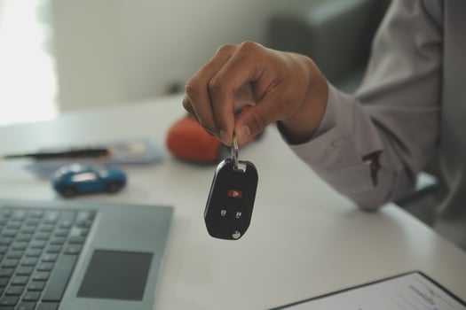 Young man receives a key from car salesman. After agreeing to a contract for rent or sale of a car at workshop, loan car, insurance, sale, buying car and finance concept. photo