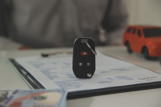 Young man receives a key from car salesman. After agreeing to a contract for rent or sale of a car at workshop, loan car, insurance, sale, buying car and finance concept. photo