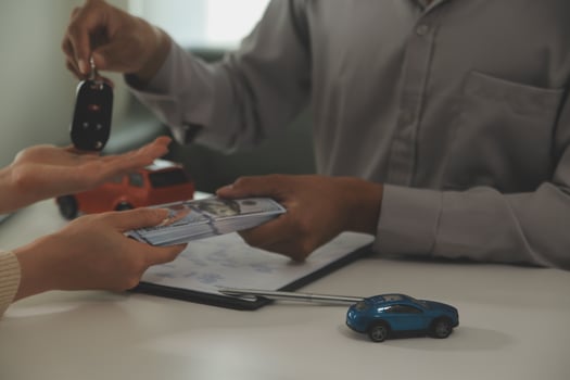 Young man receives a key from car salesman. After agreeing to a contract for rent or sale of a car at workshop, loan car, insurance, sale, buying car and finance concept. photo
