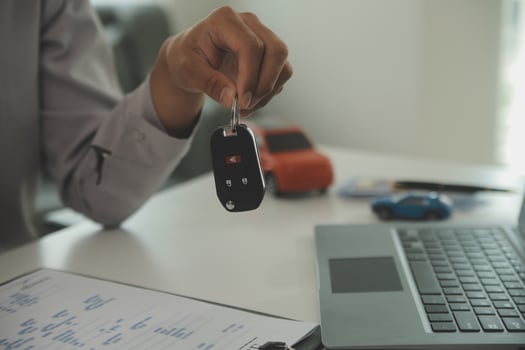 Young man receives a key from car salesman. After agreeing to a contract for rent or sale of a car at workshop, loan car, insurance, sale, buying car and finance concept. photo