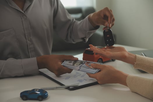 Young man receives a key from car salesman. After agreeing to a contract for rent or sale of a car at workshop, loan car, insurance, sale, buying car and finance concept. photo