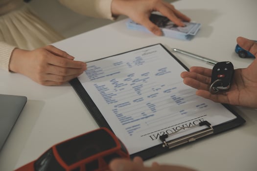 Young man receives a key from car salesman. After agreeing to a contract for rent or sale of a car at workshop, loan car, insurance, sale, buying car and finance concept. photo